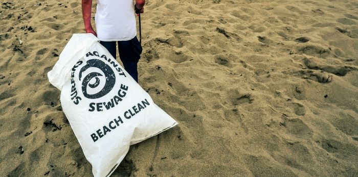 A person on the beach with a bag of rubbish