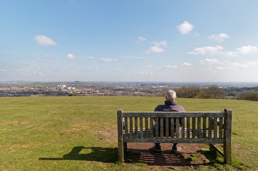 A main sitting on a bench in the Lickey Hills Country Park admiring the view from Beacon Hill.