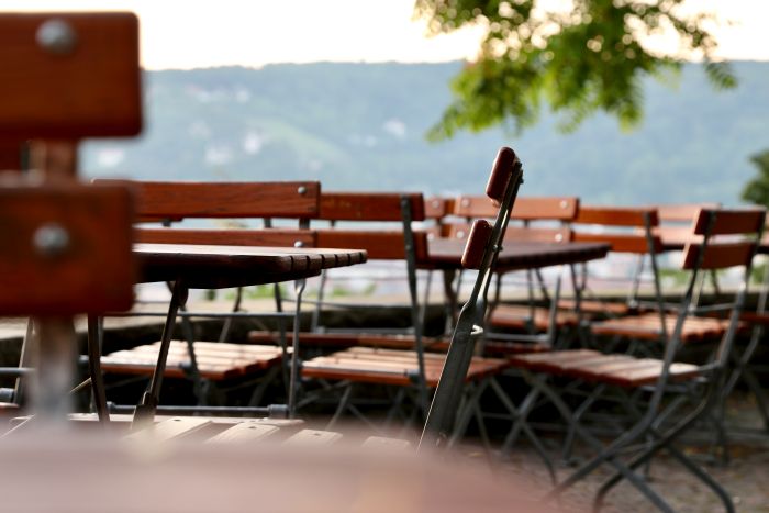Tables and chairs outside against a blurry green landscape.