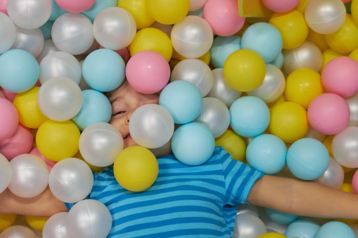 A child in a ball pit covered with colourful balls