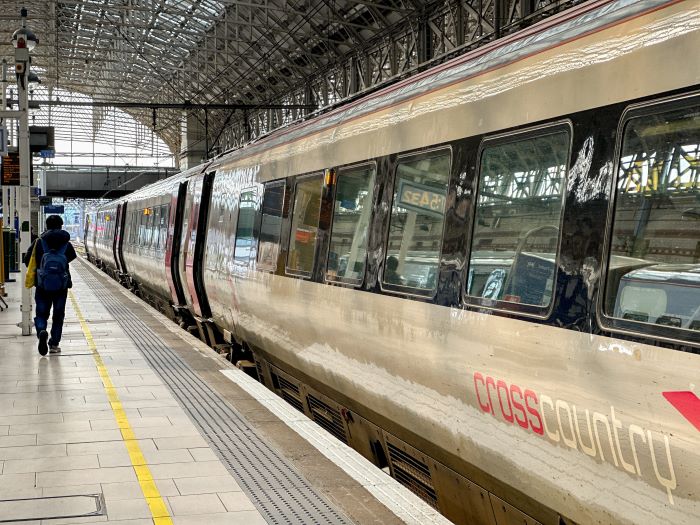 A person walking past a CrossCountry train at Manchester Piccadilly station.