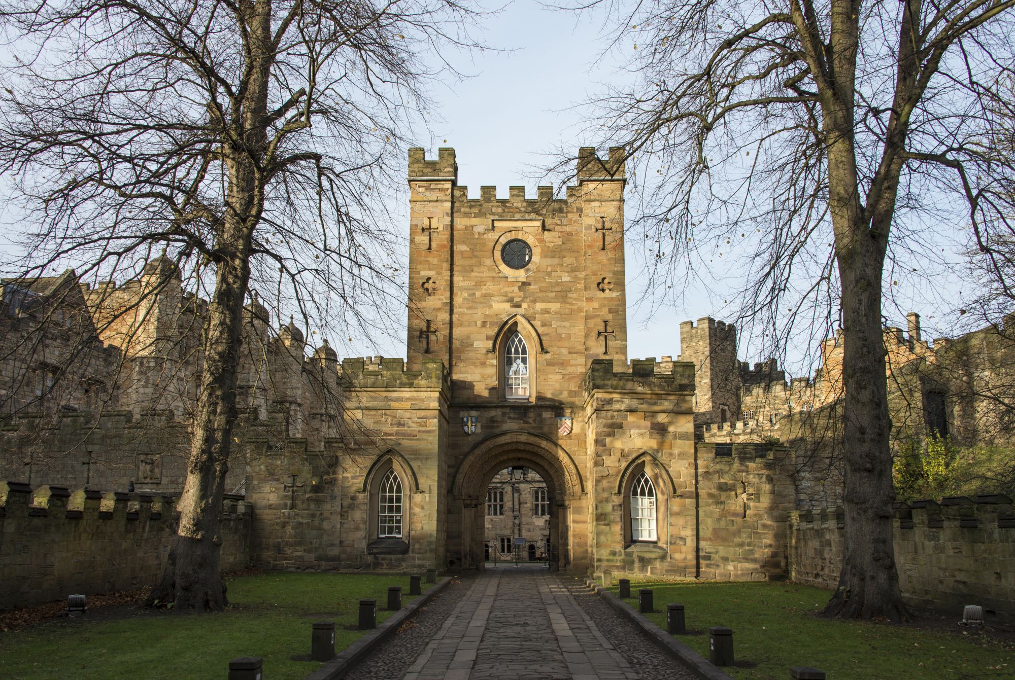 Durham Castle entryway, with a stone path leading through a gate into the Norman fortress style castle.