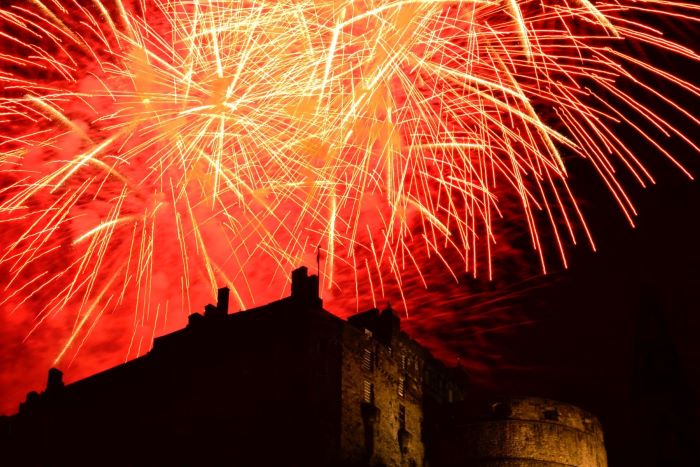 Night sky lit up with red fireworks over Edinburgh Castle