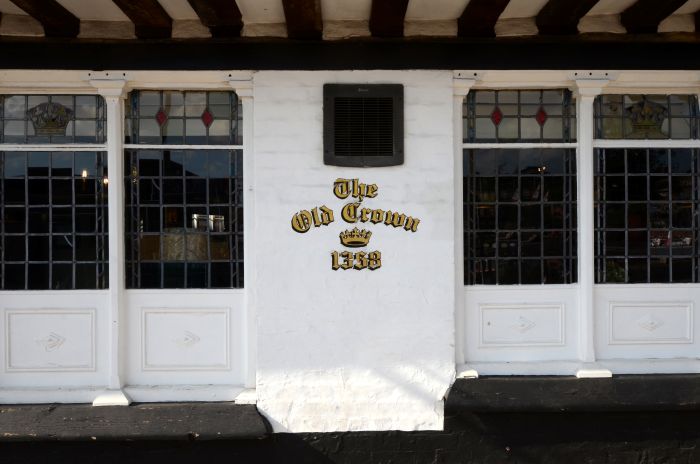 Close-up of The Old Crown pub with white walls, stained glass windows, and the pub's name in gold lettering.