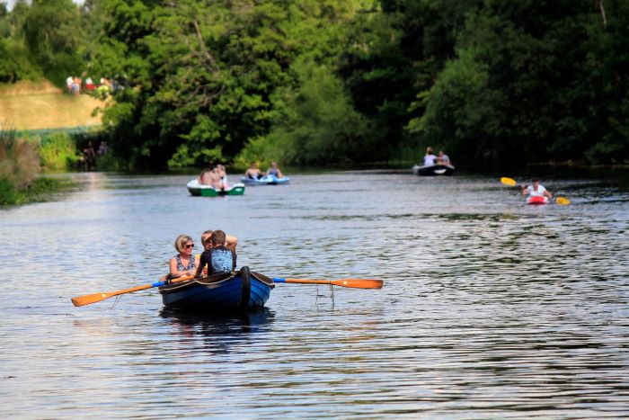 Groups of people boating on the River Leam in summer.