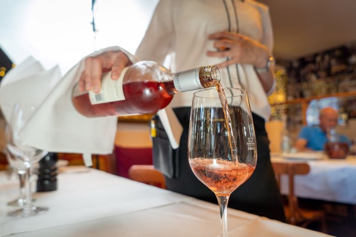 A waiter pouring a glass of rose