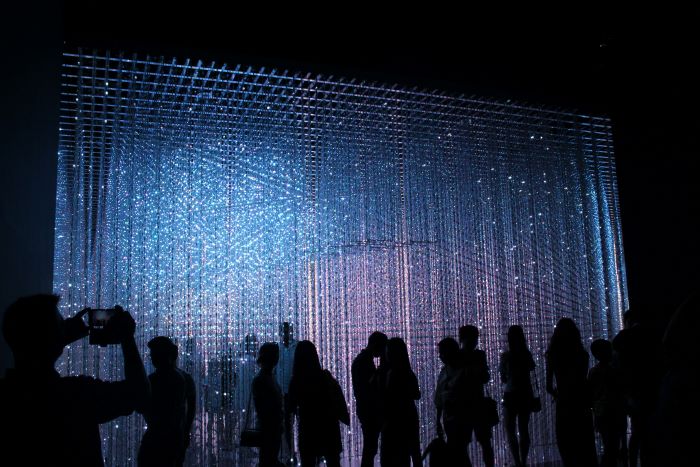 Visitors observing a light installation.