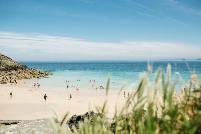 A sunny beach in St Ives with plenty of tourists.