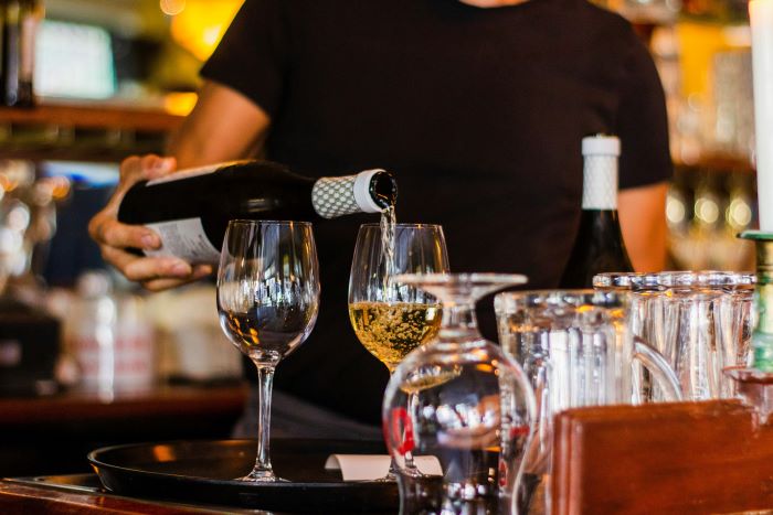 A person pouring white wine into a glass